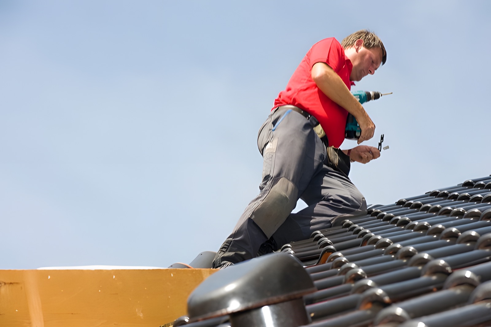 Dachdecker arbeitet am First vor blauem Himmel