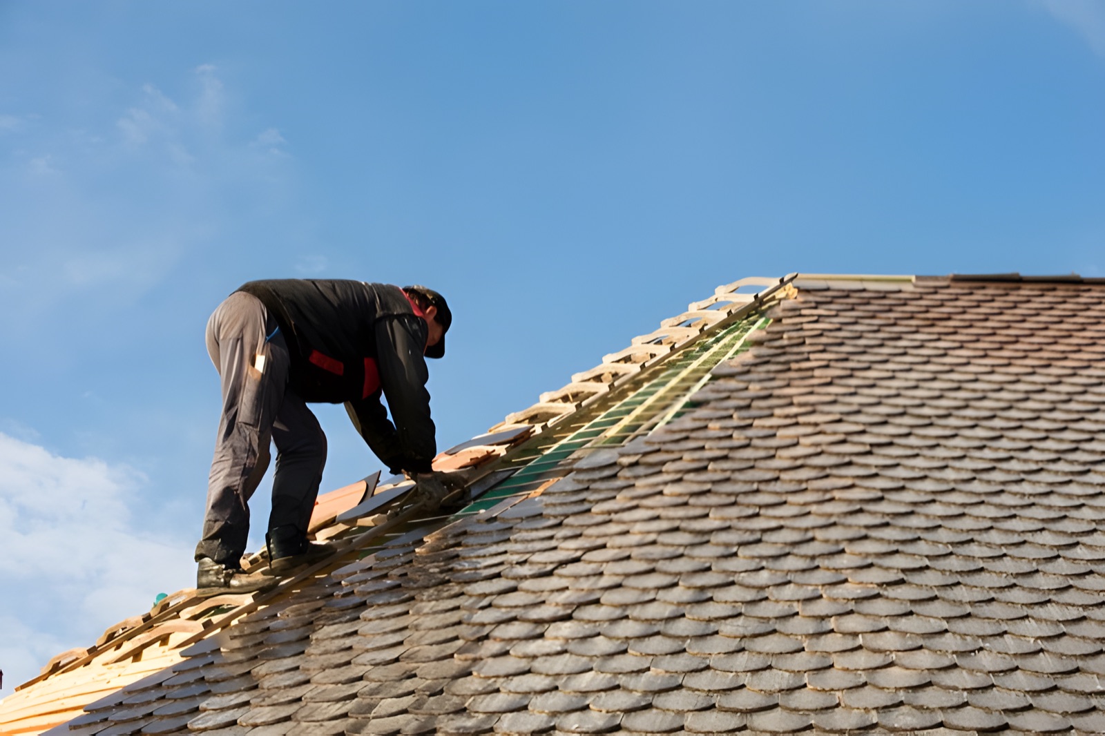 Dachdecker prüft die Fläche eines älteren Daches bei der Sanierung